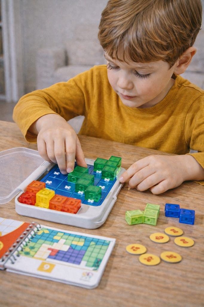 Test et comparatif des meilleurs jeux de logique et d’énigmes pour enfants enfant concentré résolvant un jeu de logique éducatif à la maison